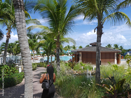 Woman on Vacation, Walking Through a Luxury Caribbean Hotel Resort in the Turks and Caicos Islands - Palm Trees and Swimming Pool in the Distance