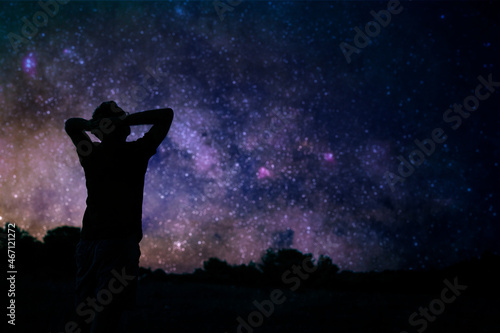 Silhouette of a man enjoying countryside under the starry skies.