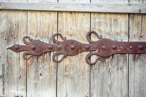 The wooden door is decorated with a decorative element of wrought iron in the Russian style. The lining on the gate leaf is forged from iron in the Old Russian style. 