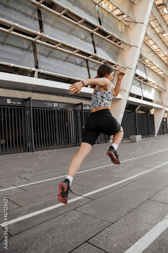Teenage girl jumping near stadium outdoors of the city background