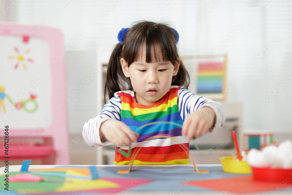 young girl making paper rainbow craft for homeschooling