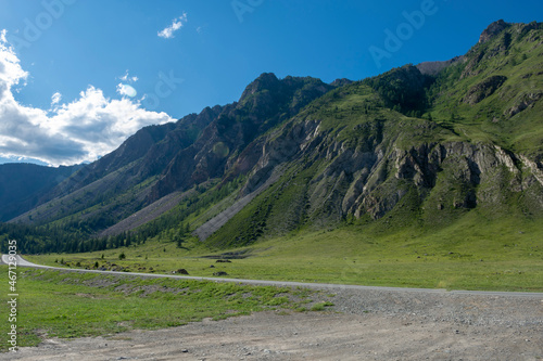 peaks of mountains against the sky with white clouds. Summer sunny day. Mountain asphalt road © Вячеслав 