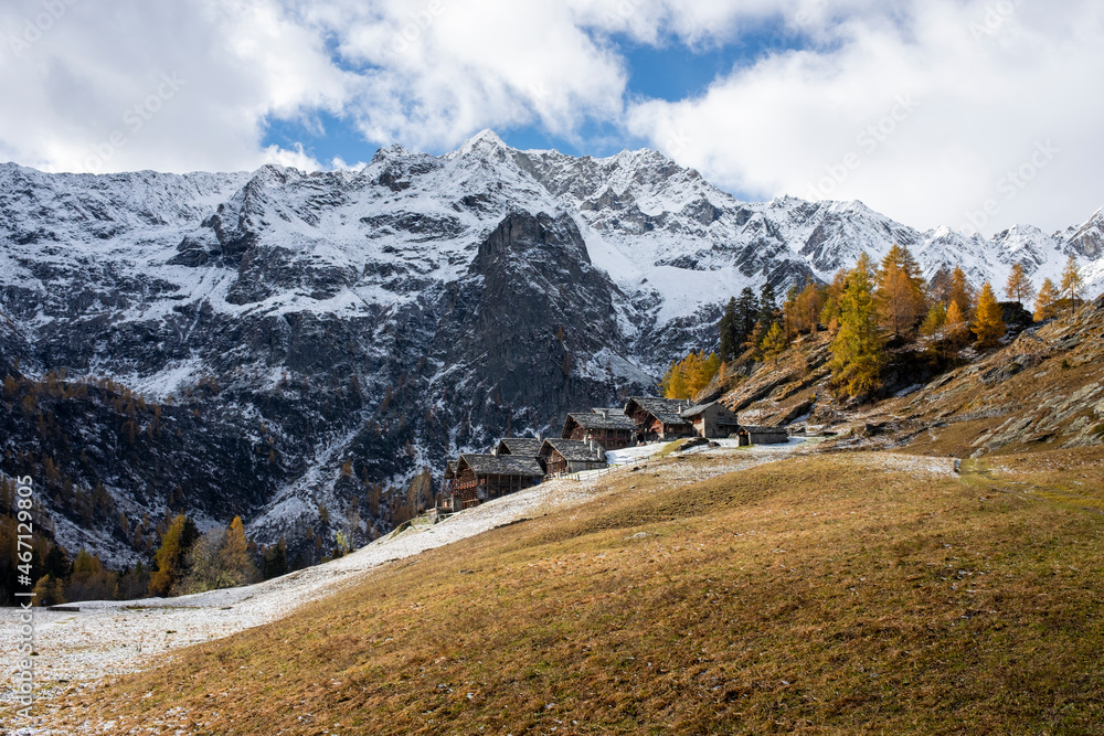 Alpine landscape with traditional wooden houses. Seasonal autumnal scenery in highlands with the first snow of the season. Landscape of the Italian Alps in Piedmont. Otro Valley, Valsesia. 