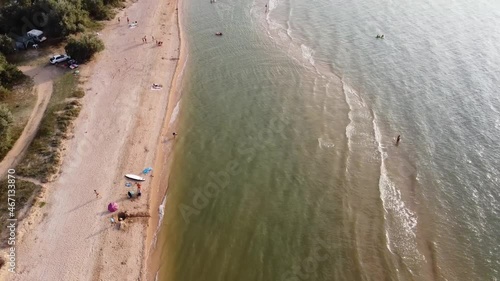 Aerial view of sandy beach during golden hour. Dolly and tilt up.