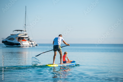 Canvas Print Father and daughter riding SUP stand up paddle on vacation.
