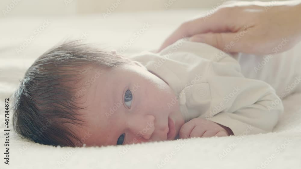Close-up portrait of a young baby who has recently been born. Newborn infant boy at home. Window light.
