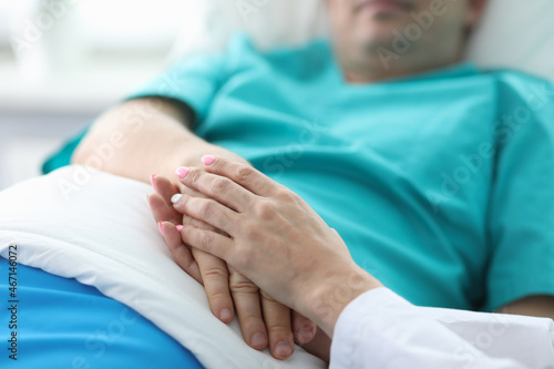 Doctors hands hold hands patient lying in ward