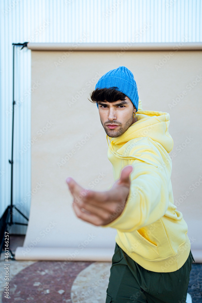 Young man wearing knit hat dancing against in front of backdrop Young man wearing knit hat dancing against in front of backdrop