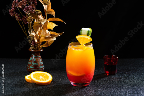  GLASSES WITH COCKTAIL SEX ON THE BEACH, A VASE OF FLOWERS NEXT TO THE DRINK, ON A DARK BACKGROUND photo