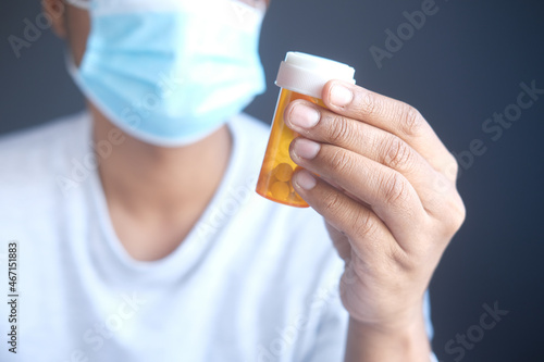 young man in face mask holding medical pills 