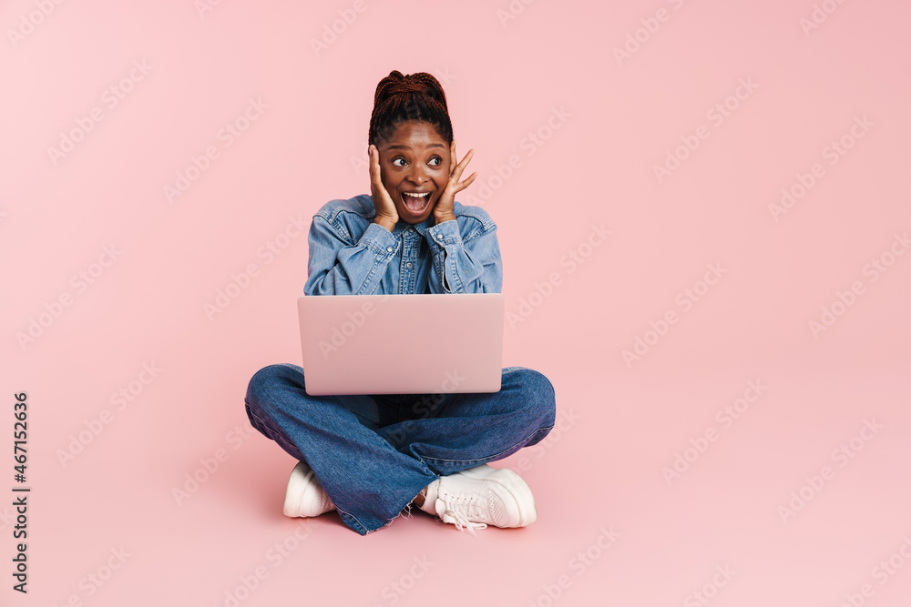 Black woman expressing surprise and using laptop while sitting on floor Black woman expressing surprise and using laptop while sitting on floor