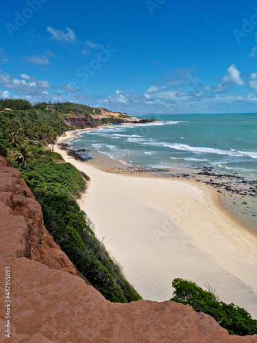 Beautiful image of the coast, with the cliff in the foreground and the beach and the blue sky in the background. © Celso