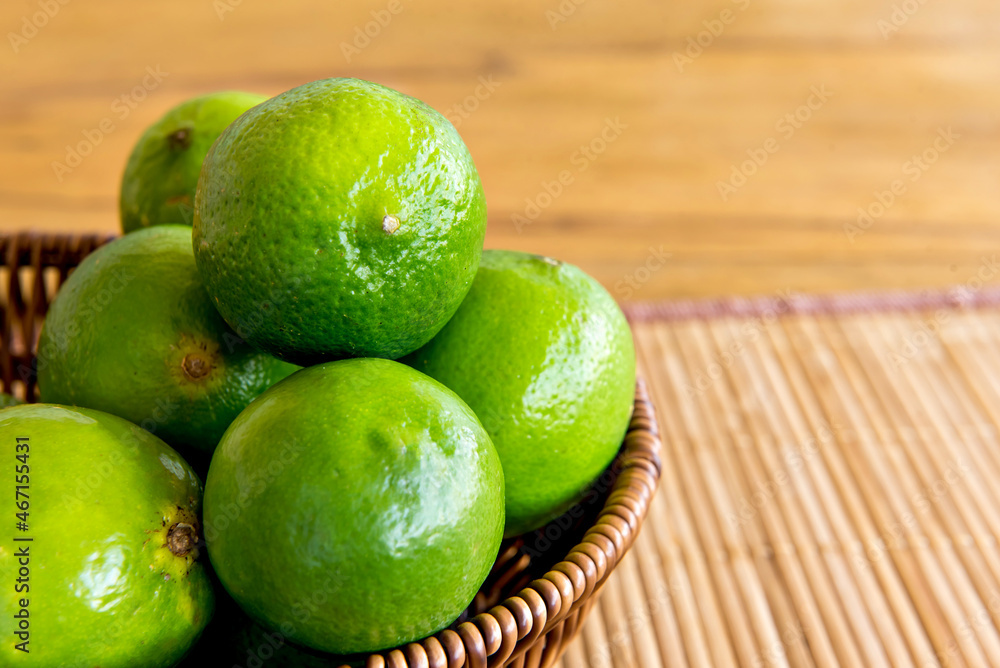 Basket with green lemons on a wooden table. Basket with green lemons on a wooden table.