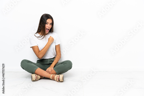 Teenager girl sitting on the floor celebrating a victory
