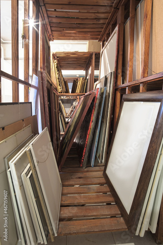 Wooden shelves full of pictures, frames and art equipment. Art gallery storage