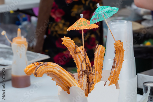 Homemade crunchy churros in paper box at summer outdoor food market - close up view. Traditional Spanich cuisine, cookery, gastronomy and street food concept