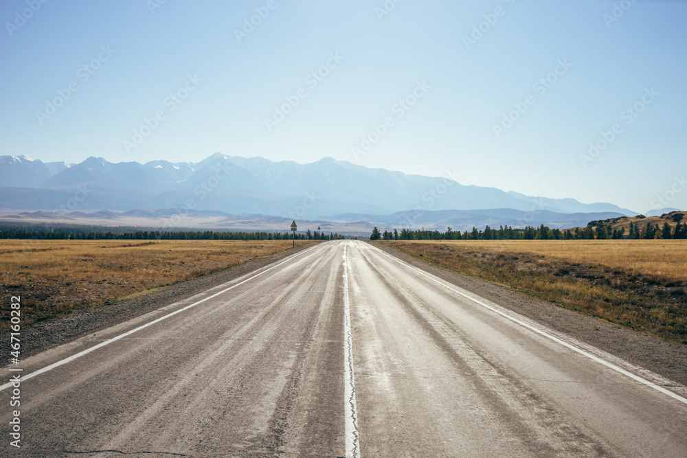 A direct road to the mountains. The path is clear asphalt road in the countryside.