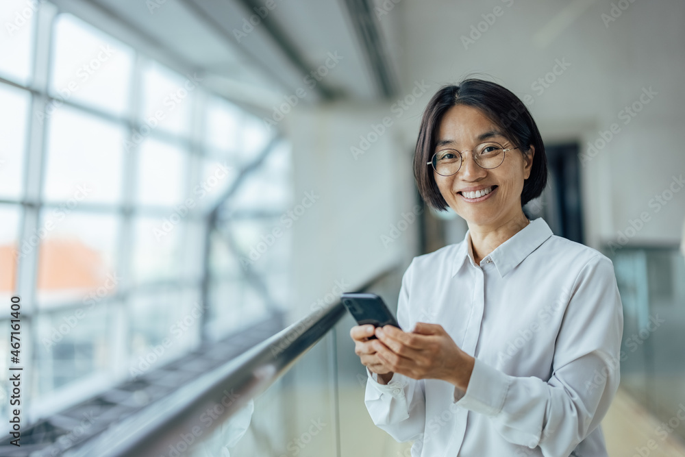 Shot of an asian woman in her 40s, using her new smartphone Shot of an asian woman in her 40s, using her new smartphone