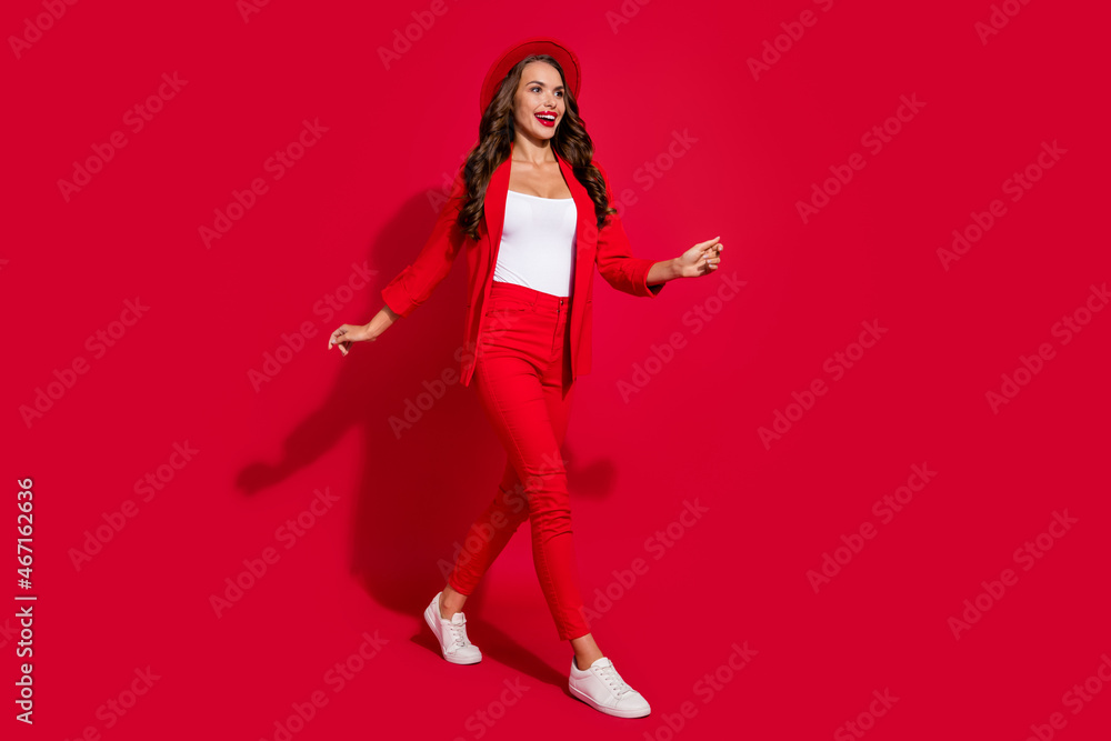 Photo of charming sweet young lady dressed suit blazer headwear walking looking empty space smiling isolated red color background Photo of charming sweet young lady dressed suit blazer headwear walking looking empty space smiling isolated red color background