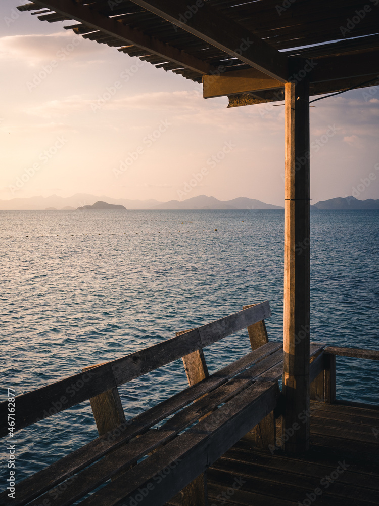 Scenic view of peaceful blue water bay with layer islands in evening before sunset from wooden pier pavilion foreground. Koh Mak Island, Trat, Thailand. Selective focused on sea.