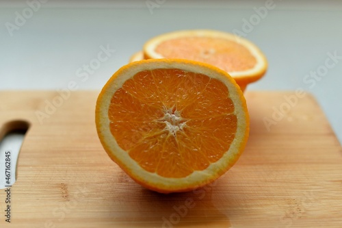 Half and slices of orange on a wooden board. Sliced citrus. A piece of fresh juicy fruit. 