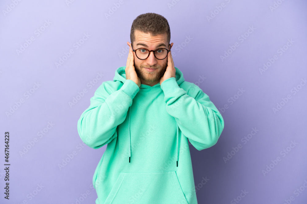 Young handsome caucasian man isolated on purple background frustrated and covering ears Young handsome caucasian man isolated on purple background frustrated and covering ears