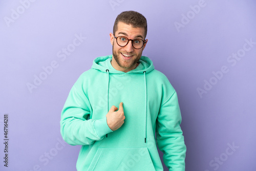 Young handsome caucasian man isolated on purple background with surprise facial expression