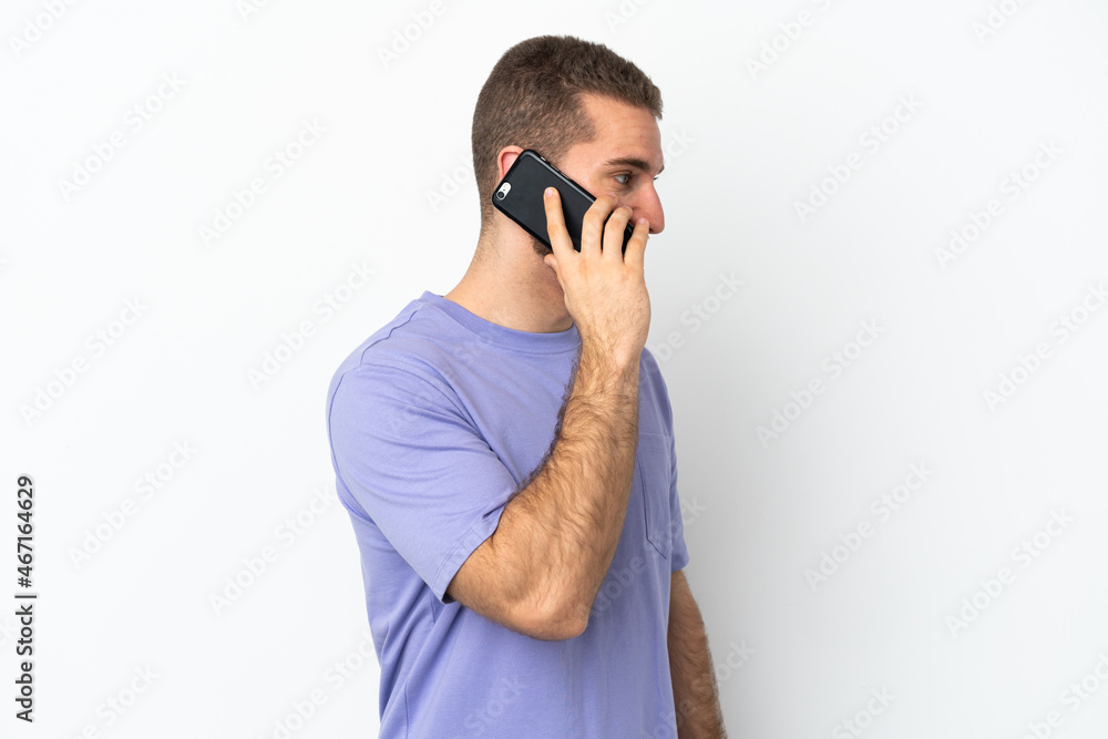 Young handsome caucasian man isolated on white background keeping a conversation with the mobile phone with someone Young handsome caucasian man isolated on white background keeping a conversation with the mobile phone with someone