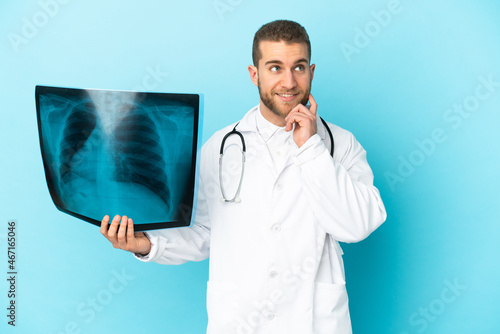 Professional traumatologist isolated on blue background thinking an idea while looking up