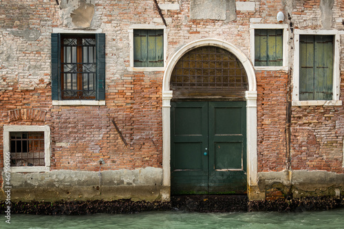 Entrance in an old brick wall near water in Venice © Stefan