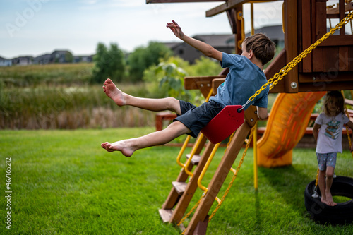 Canvas Print Caucasian male boy jumping from a swing set in midair falling