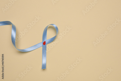 Light blue ribbon with paper blood drop on beige background, top view and space for text. Diabetes awareness