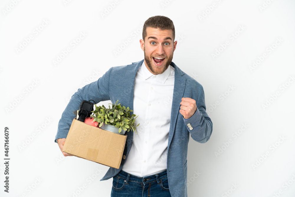 Young caucasian making a move while picking up a box full of things isolated on white background celebrating a victory in winner position Young caucasian making a move while picking up a box full of things isolated on white background celebrating a victory in winner position