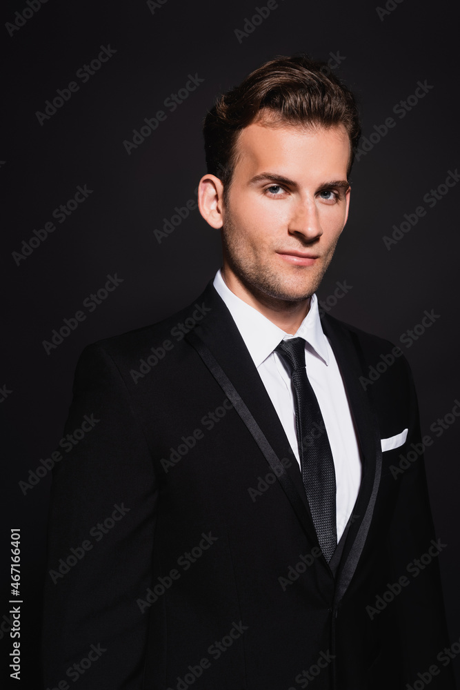 young confident man in elegant suit looking at camera on black young confident man in elegant suit looking at camera on black