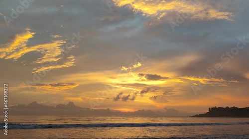 Beautiful evening orange sunset view with clouds above the sea waves from the beach