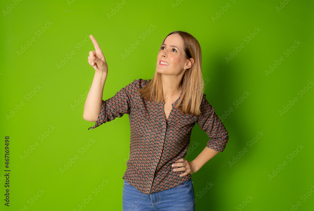 Young woman in casual shirt pointing finger up isolated over green background. Young woman in casual shirt pointing finger up isolated over green background.