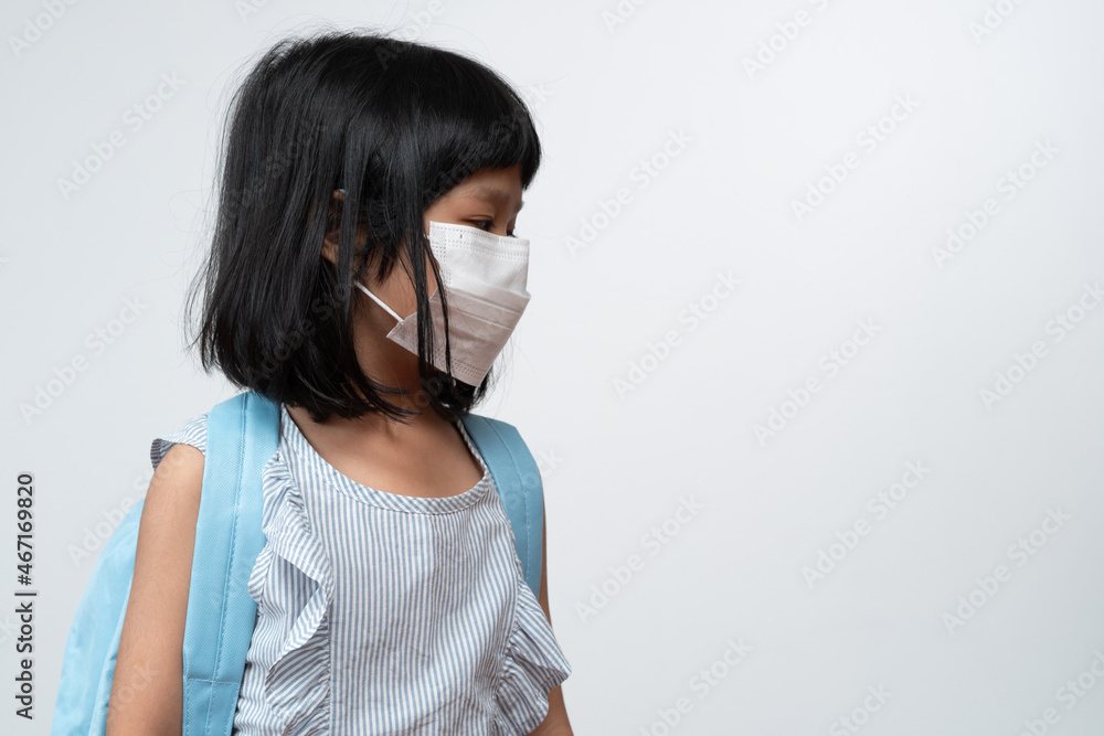 Portrait of Asian girl kid with protective face mask and school backpack ready for new school year with pandemic restrictions. Concept of kid going back to school and new normal lifestyle Portrait of Asian girl kid with protective face mask and school backpack ready for new school year with pandemic restrictions. Concept of kid going back to school and new normal lifestyle