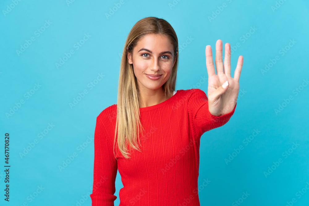 Young blonde woman isolated on blue background happy and counting four with fingers Young blonde woman isolated on blue background happy and counting four with fingers