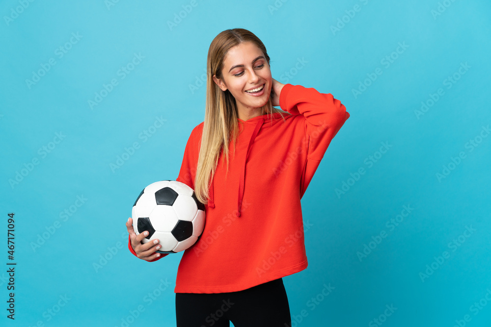 Young football player woman isolated on blue background laughing