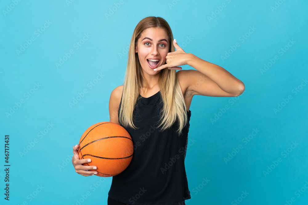 Young woman playing basketball isolated on white background making phone gesture. Call me back sign Young woman playing basketball isolated on white background making phone gesture. Call me back sign