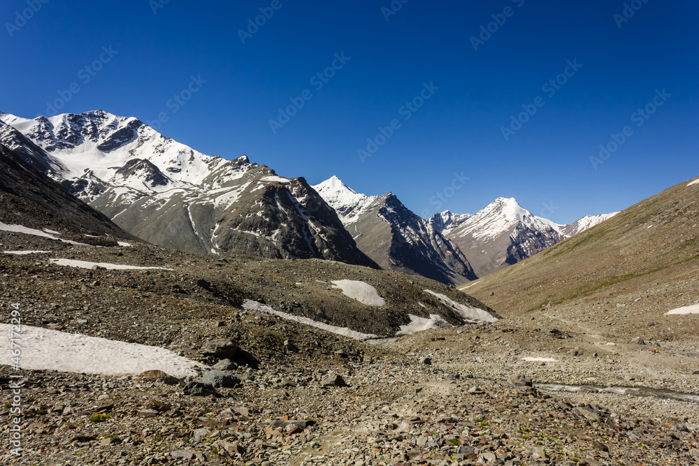 Fototapeta premium A view of the snow capped Himalayan mountain range on the trekking trail between Darcha and Padum in the Zanskar valley.