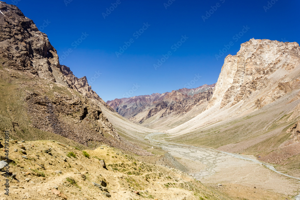Barren mountains of the cold desert wilderness of the Zanskar valley under a blue sky on a sunny day in the Ladakh region in North India.