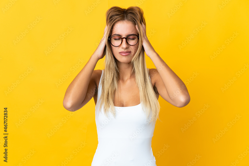Young blonde woman isolated on yellow background with headache Young blonde woman isolated on yellow background with headache
