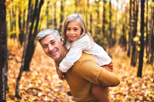 Father and daughter having fun in the autumn colorful forest