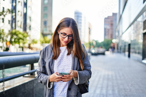 Woman texting on smartphone while walking on sidewalk