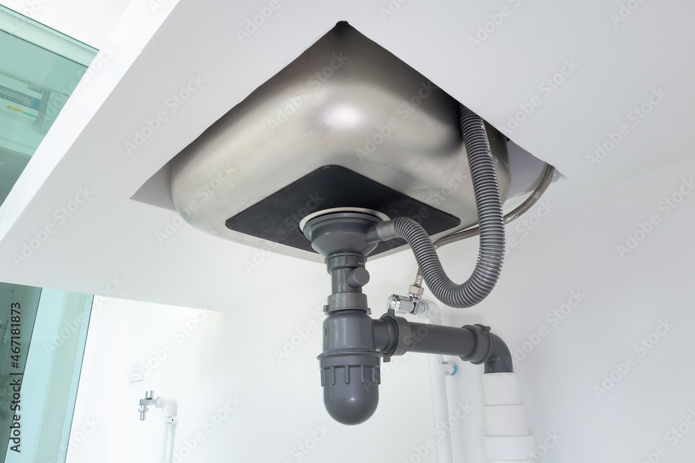 Drain pipe or sewer under kitchen sink. Pvc plastic pipe and flexible  supply tube connection to