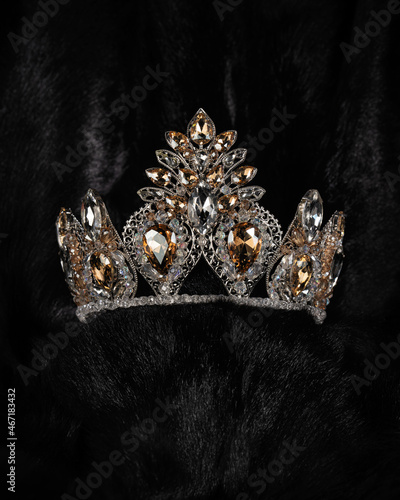 beautiful silver crown with a yellow stone for a beauty pageant on a black background, accessory headdress, close-up photo