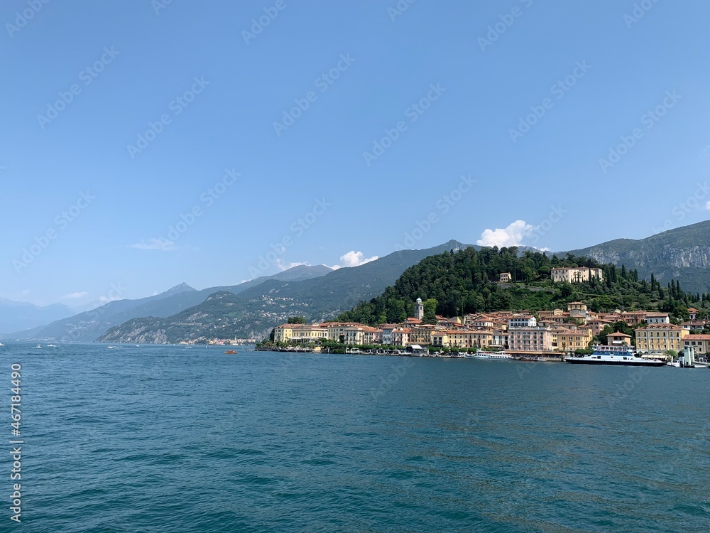 View of Bellagio city skyline from arriving boat. Varenna town and mountains in the background. Bellagio is a famous sightseeing and tourism place at Lago di Como. Bellagio, Como Lake, Italy