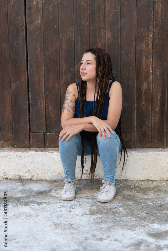 Hispanic woman sitting near wooden wall Hispanic woman sitting near wooden wall