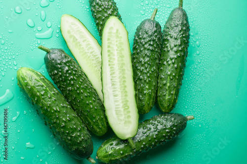 Set of fresh whole and sliced cucumbers on a green background with water drops. Garden cucumber wallpaper backdrop design